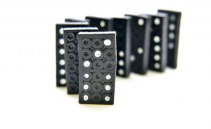 Schwarze Dominosteine, hochkant in einer Reihe aufgestellt.