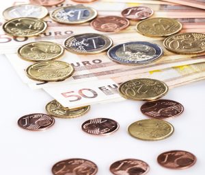 Mehrere Cent-Stücke und Euro-Münzen und Euro-Scheine auf einer Tischplatte.